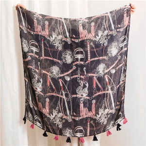 Detail of black equestrian print scarf featuring tassels and horse bit patterns