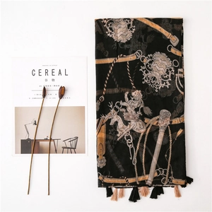 Detail of vintage black scarf with gold coat of arms print and tassel edge on white base