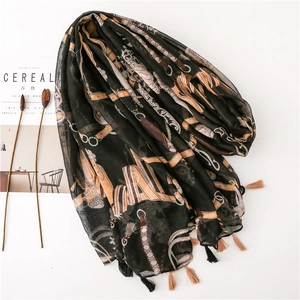 Detail of black equestrian print scarf with gold belt motifs and elegant fringe trim