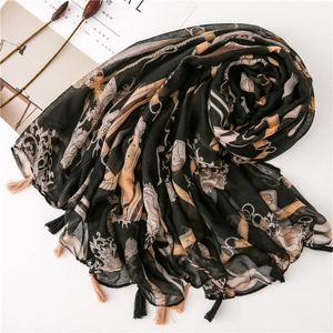Detail of vintage black shawl with gold chain print and fringe tassels on white background