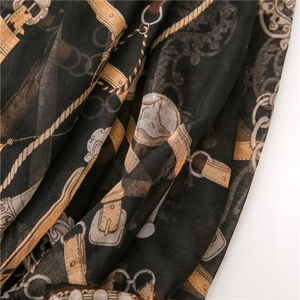 Close-up of black silk scarf with gold chain print and soft textured fabric detail