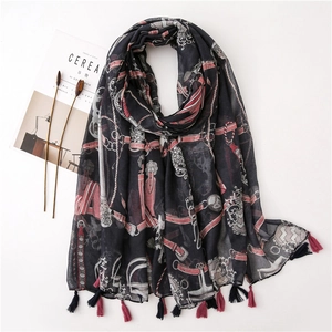 Vintage style black scarf with pink belt patterns and tassels on a flat lay background
