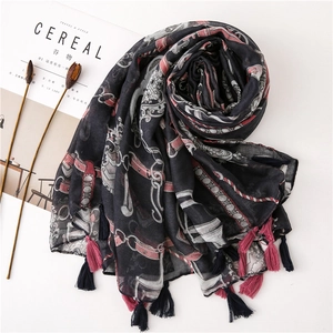 Detail of a lightweight black printed scarf with tassel charms and vintage chain patterns