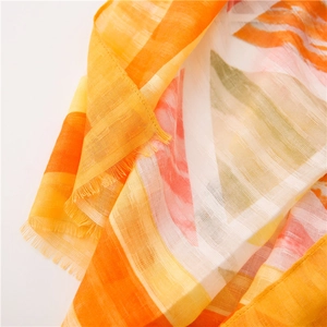 Detail of colorful geometric cotton linen scarf with soft fringe edges and translucent texture