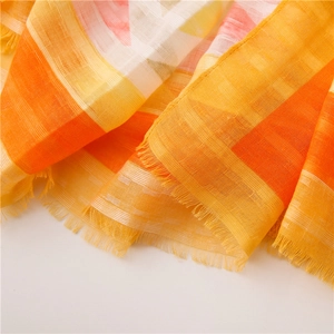 Detailed close-up of thin orange and yellow plaid linen shawl with delicate fringe edge
