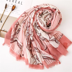 Dettaglio di sciarpa stampata rosa e beige con filo d'argento e bordi a frange