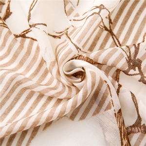 Dettaglio di una sciarpa in chiffon leggero in tessuto bianco con motivi a righe marroni