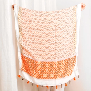 Detail showing Bohemian linen scarf with orange geometric patterns and tassel edges