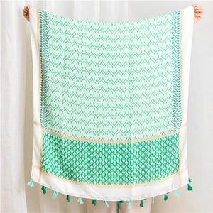 Detail of bohemian cotton linen scarf featuring mint green geometric patterns and tassels