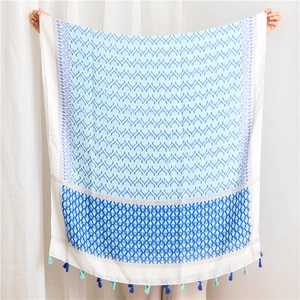 Detailed view of bohemian linen scarf with blue geometric patterns and tassel edges