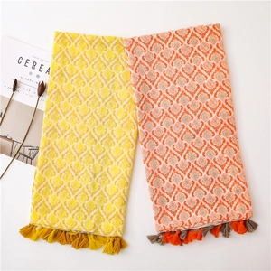 Close-up of bohemian linen scarf showing vintage damask patterns and fringed tassel edges