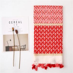 Flat lay of pink and red bohemian cotton linen scarf with tassels and floral magazine