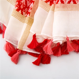 Detail of bohemian cotton linen scarf featuring red ethnic patterns and tassel fringe edge