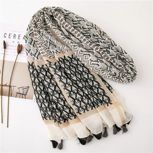 Detail of bohemian printed scarf with geometric patterns and fringe tassels on white surface