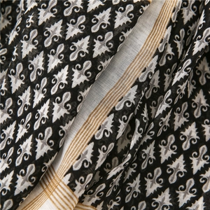 Detail of bohemian cotton linen scarf featuring black floral patterns and striped borders