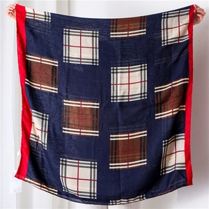 Detail showing navy blue checkered scarf with red trim in a lightweight fabric