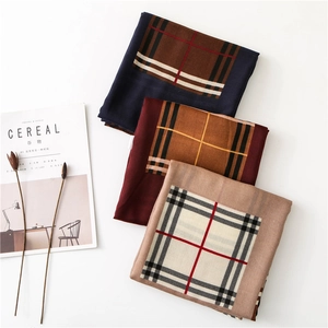 Close-up of three plaid cotton-linen scarves in navy, wine red, and cream beige