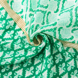 Detail of vibrant green cotton linen scarf with bohemian geometric patterns and tassels