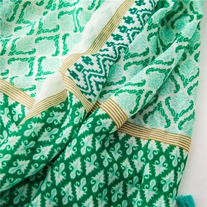 Detail of vintage ethnic patterns and tassel edges on green linen cotton beach shawl