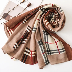 Flat lay of khaki plaid scarf with fabric texture details and lifestyle props
