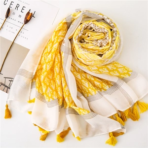 Close-up of bohemian linen scarf with yellow geometric patterns and handmade tassels