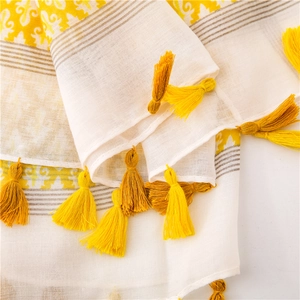 Detailed macro view of white cotton linen scarf with yellow geometric patterns and tassels