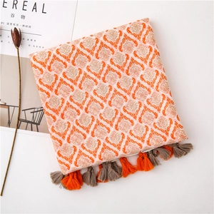 Detail of orange bohemian linen scarf with geometric patterns and handmade tassels