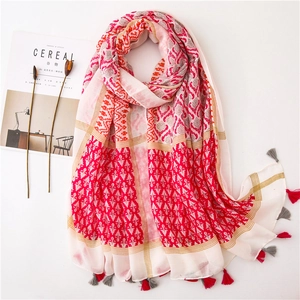 Close-up of ethnic red cotton linen shawl with colorful prints and tassel fringe detail