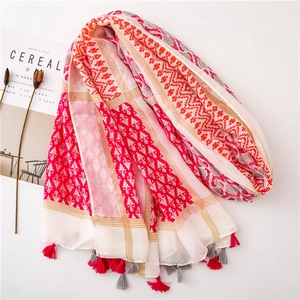 Detail of red and pink ethnic printed scarf featuring geometric patterns and soft tassels