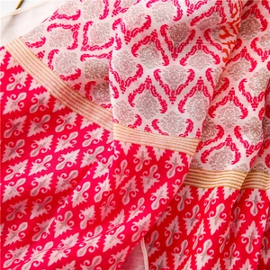 Macro shot of red cotton linen scarf featuring vintage damask patterns and fringe detail