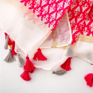 Detail of bohemian cotton linen scarf featuring floral patterns and decorative tassels