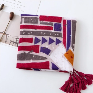 Close-up of geometric printed beach shawl featuring dark red tassel trim and soft fabric