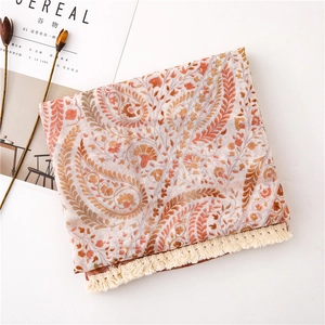 Détail de l'écharpe en coton et lin à motif paisley avec franges aux tons orange chaud