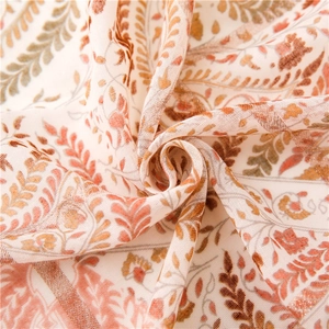 Détail macro du motif floral bohème sur la texture légère du foulard en coton et lin
