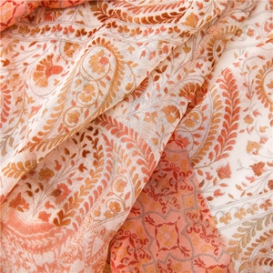 Gros plan détaillé d'un châle à motif paisley avec fils métalliques et tons corail