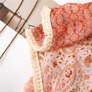 Gros plan du motif paisley et des franges sur un châle en coton et lin orange chaud