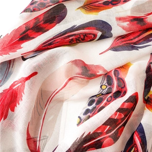 Detailed view of lightweight cotton scarf with colorful feather prints and gold thread