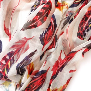 Close-up of lightweight cotton scarf showing colorful feather print and fine fringe details