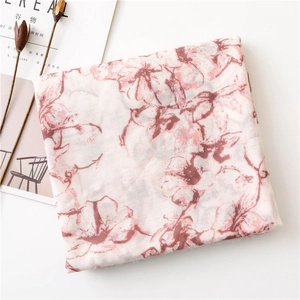 Floral print scarf in beige with pink flowers, folded neatly on a magazine background