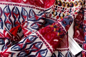 Detail of bohemian red and blue printed scarf showing fringe and 100% acrylic fabric texture