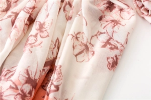 Close-up of floral scarf fabric with pink blossoms on a cream-colored soft texture