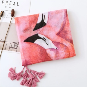 Détail d'une écharpe rose imprimé flamant rose avec pompons et texture en lin