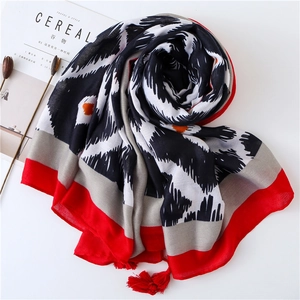 Écharpe longue géométrique avec bordure rouge et pompons sur fond minimaliste