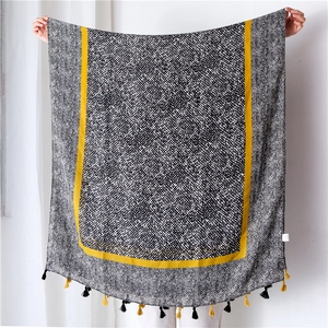 Detail of cotton linen scarf featuring black white patterns with yellow fringe tassels