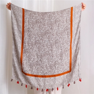 Detail of linen scarf with leopard pattern, orange borders and multicolor fringe