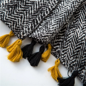 Detail of woven herringbone pattern fabric with contrasting yellow and black fringes