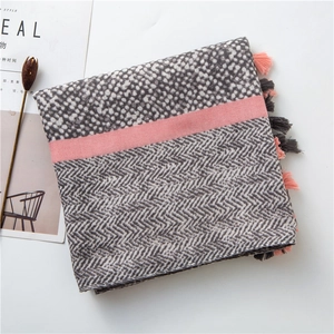 Detail of grey and white knitted scarf featuring pink stripes and decorative tassels