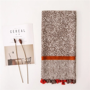 Detail of a knitted scarf with leopard print, orange stripe, and fringe tassels