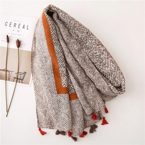 Detail of herringbone and dot pattern scarf featuring orange borders and two-tone tassels