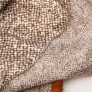 Detail of linen scarf with leopard and herringbone patterns showing fine rolled hem edge